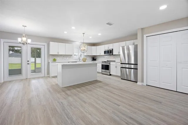 a large white kitchen with wooden floors and stainless steel appliances