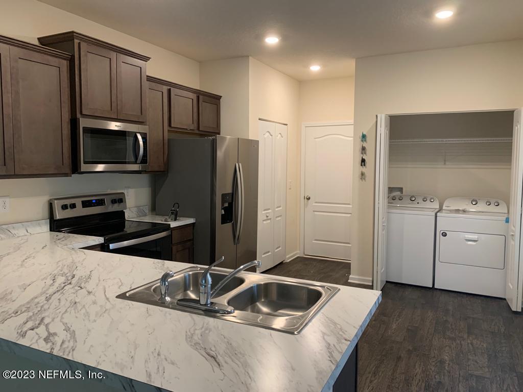 a kitchen with kitchen island granite countertop a sink stainless steel appliances and cabinets