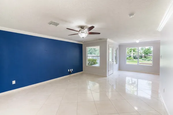 an empty room with windows and ceiling fan