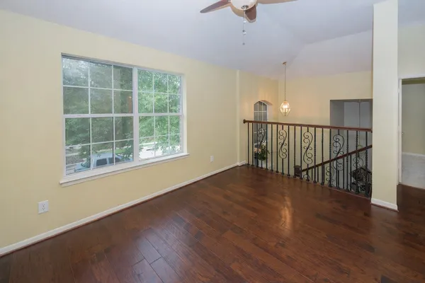 a view of an empty room with wooden floor and a window