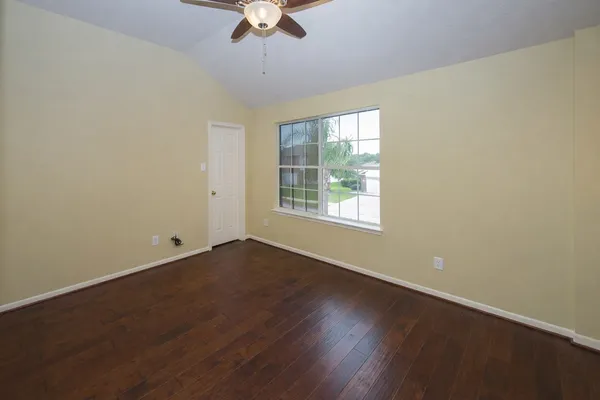 a view of an empty room with wooden floor and a window