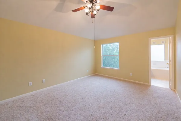 an empty room with a chandelier fan and windows