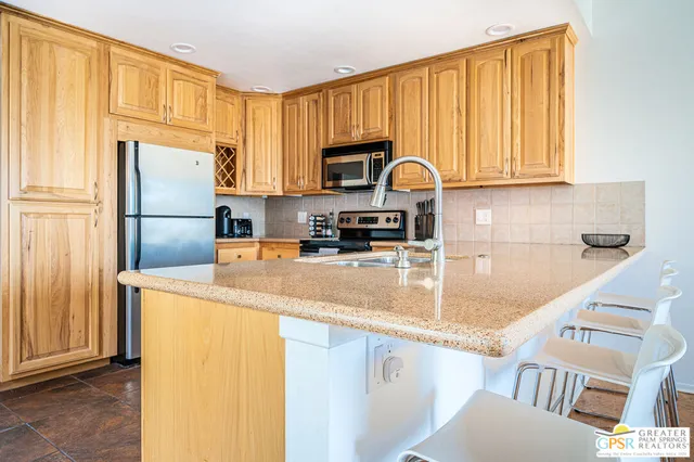 a kitchen with granite countertop a refrigerator a stove a sink and dishwasher with wooden floor