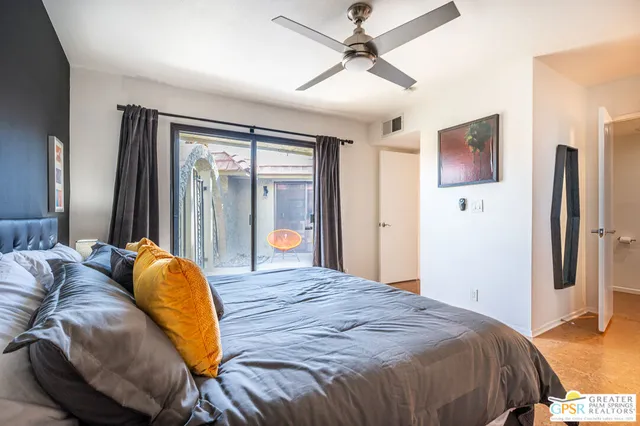 a bedroom with a bed and dresser with floor to ceiling window