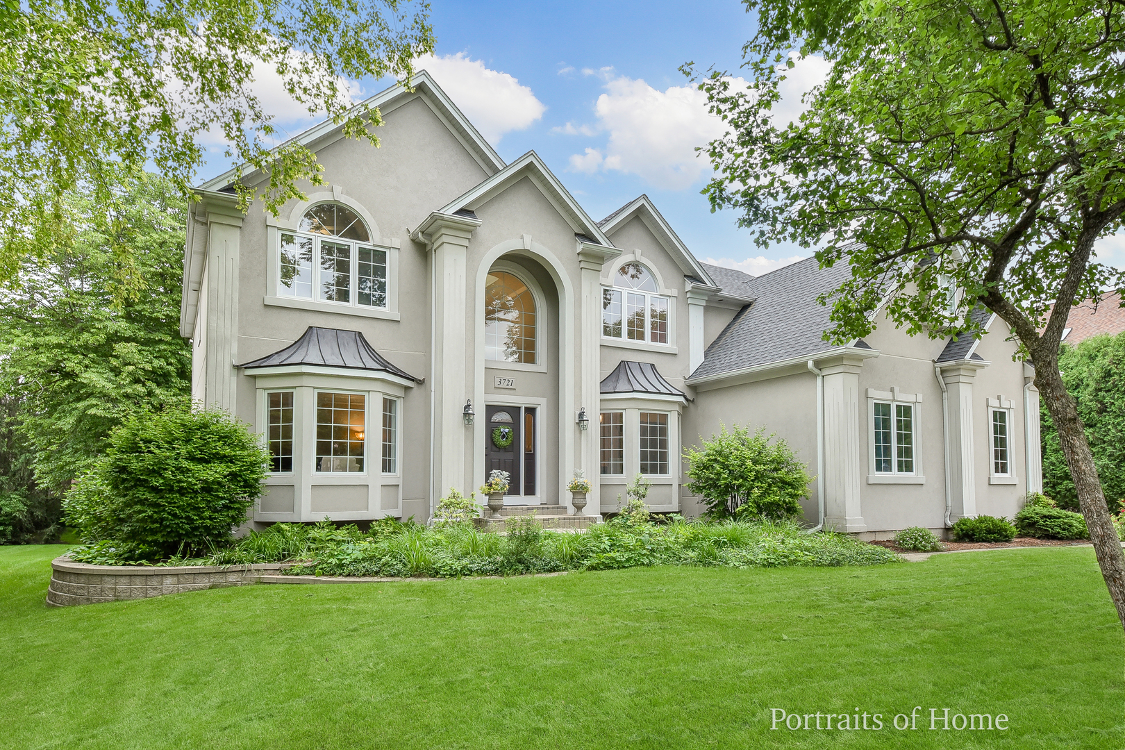 a view of a white house with a big yard and large trees