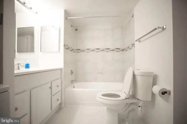 a bathroom with a granite countertop bathtub shower sink vanity and toilet
