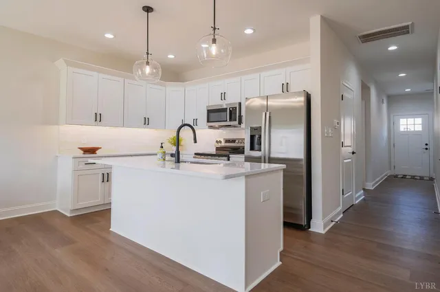 a kitchen with kitchen island a sink stainless steel appliances and wooden floor