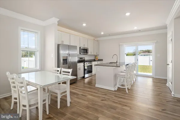 a kitchen with stainless steel appliances kitchen island granite countertop a dining table chairs refrigerator and sink