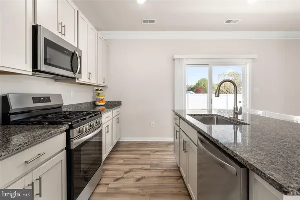 a kitchen with stainless steel appliances granite countertop a stove top oven a sink and dishwasher