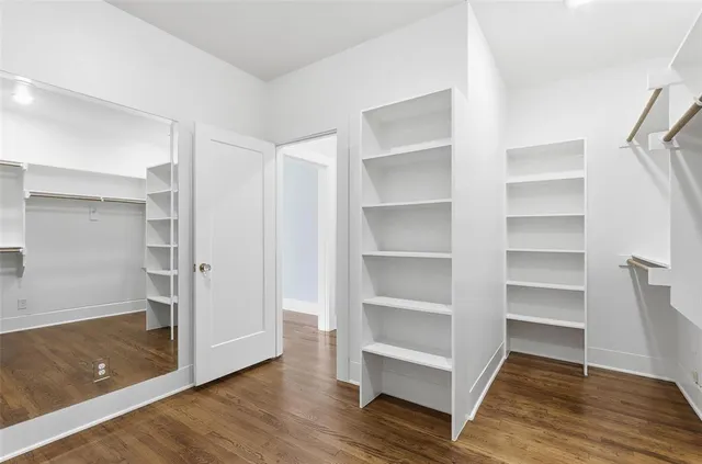 a view of an empty room with wooden floor and closet