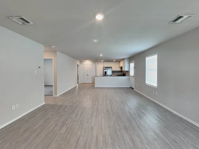 a view of empty room with wooden floor and window