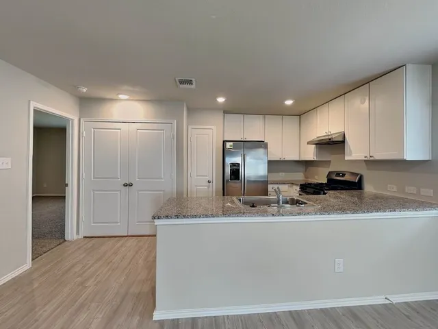 a kitchen with stainless steel appliances granite countertop a sink a refrigerator and a granite counter tops
