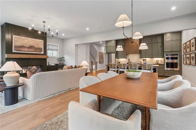 a living room with couches a dining table and kitchen view with wooden floor