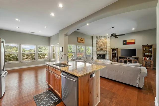 a kitchen with granite countertop a stove top oven a refrigerator and cabinets