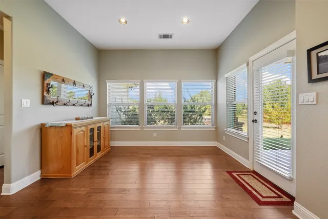 a view of an empty room with a window and wooden floor