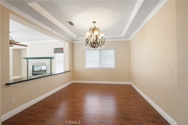 an empty room with wooden floor chandelier and windows