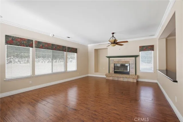 an empty room with wooden floor fireplace and windows
