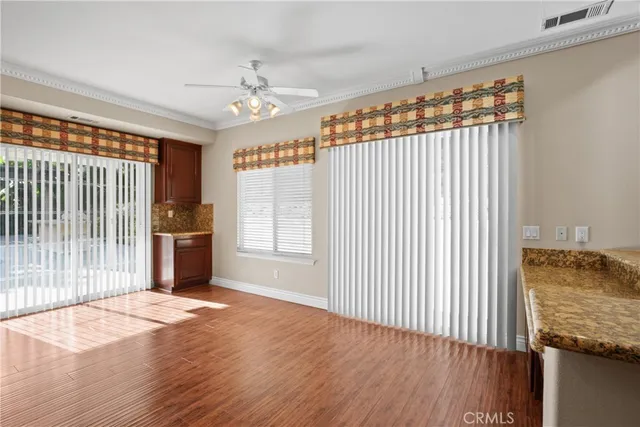a view of a livingroom with wooden floor and kitchen space