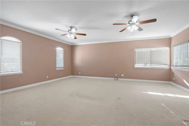 an empty room with windows and fan chandelier fan
