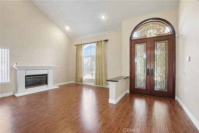 an empty room with wooden floor a fireplace and windows