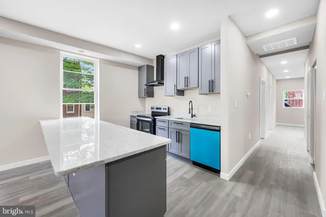 a kitchen with stainless steel appliances kitchen island wooden floors and white cabinets