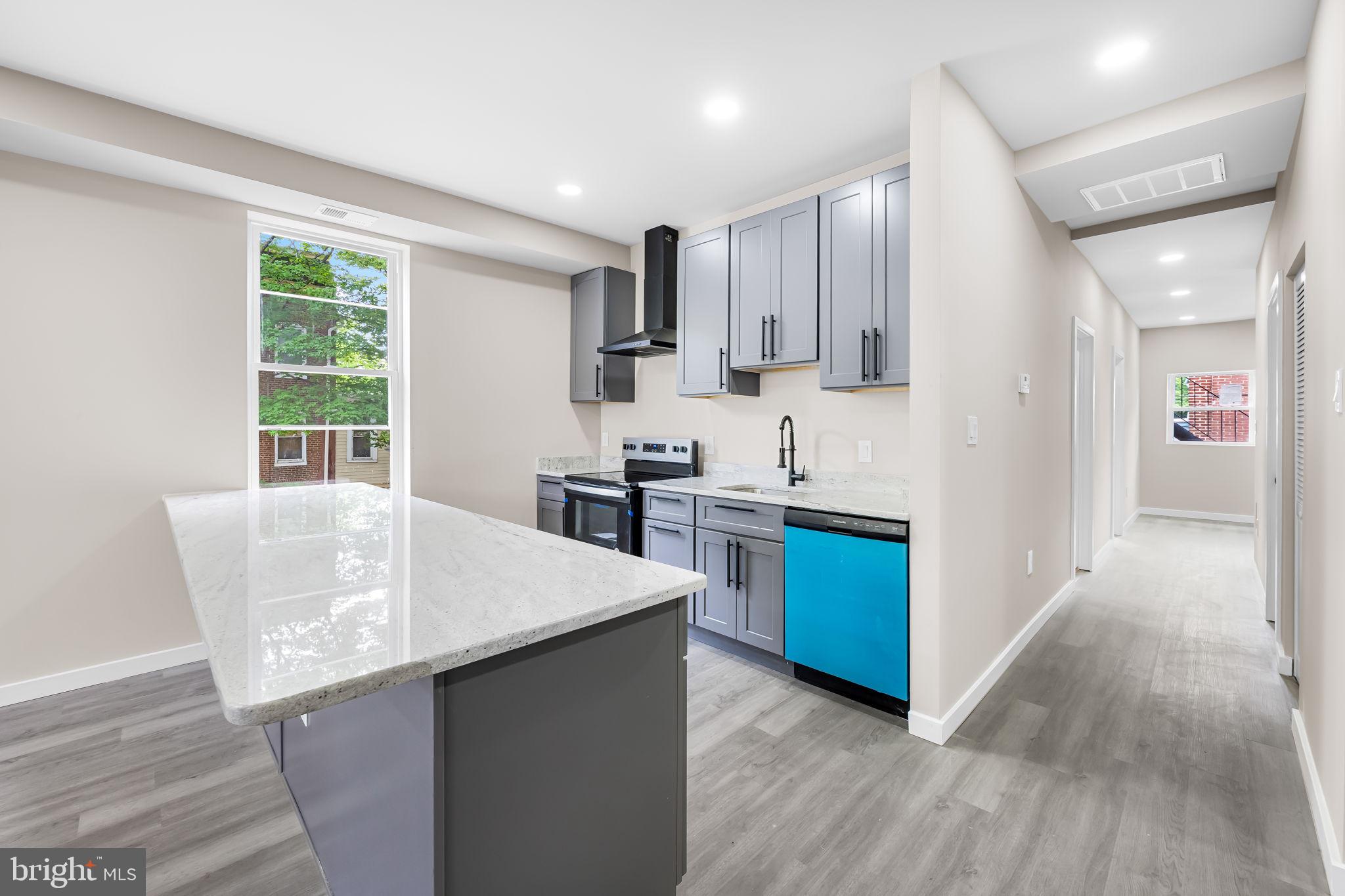815 East 33rd Street Baltimore, MD 21218 - Photo 8 of 41 a kitchen with stainless steel appliances kitchen island wooden floors and white cabinets