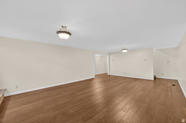 3120 North Apache Way Provo, UT 84604 - Photo 40 of 58 Spacious room featuring wood-finish flooring, neutral-toned walls, and multiple ceiling-mounted light fixtures