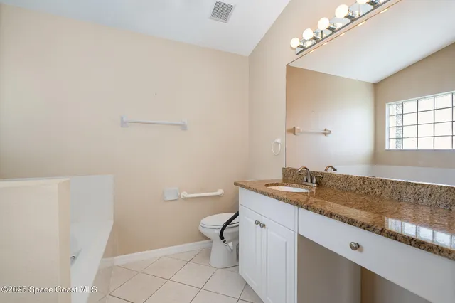 a bathroom with a granite countertop sink a toilet and a mirror