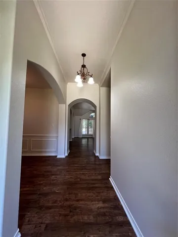 a view of a hallway with wooden floor and a large mirror