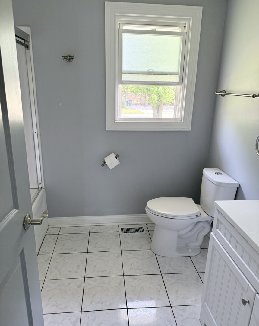 8356 South 78th Avenue Bridgeview, IL 60455 - Photo 19 of 39 a bathroom with a toilet a sink a window and a mirror