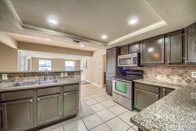 a kitchen with stainless steel appliances granite countertop a sink stove and cabinets