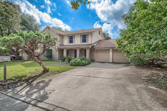 a view of a house with a yard and large tree
