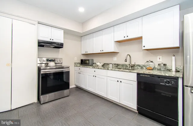 a kitchen with granite countertop white cabinets and stainless steel appliances