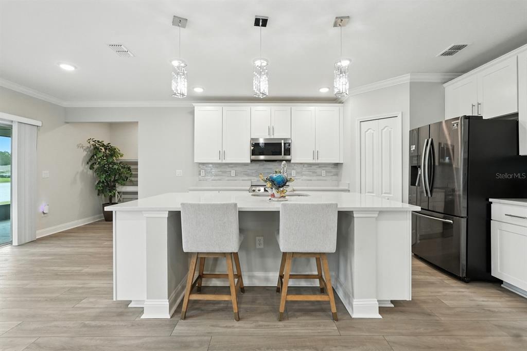28 Ridge Road Palm Coast, FL 32137 - Photo 8 of 57 a kitchen with kitchen island white cabinets and stainless steel appliances