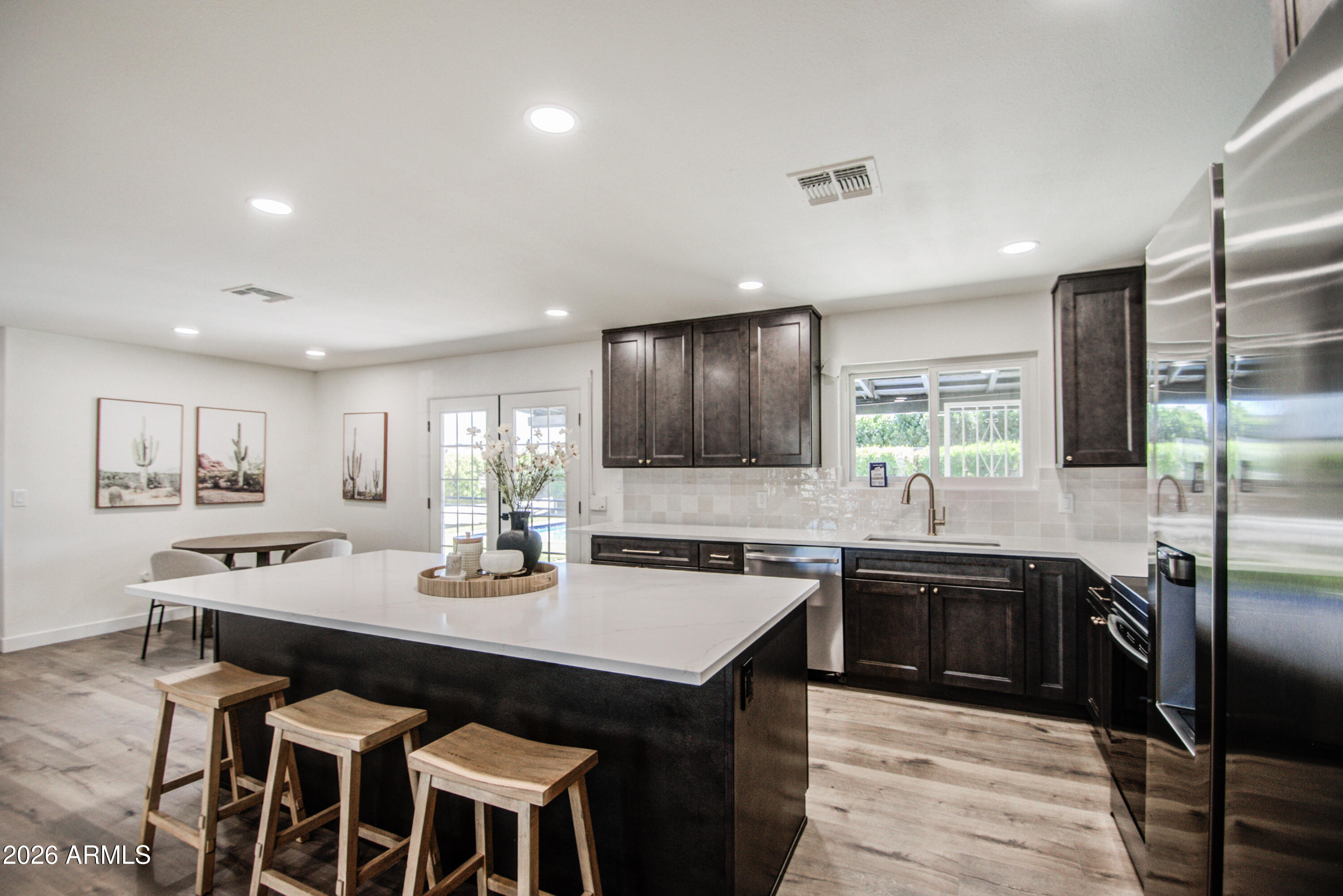 1203 West Elna Rae Street Tempe, AZ 85281 - Photo 3 of 34 a kitchen with stainless steel appliances granite countertop a kitchen island hardwood floor sink stove dining table and chairs