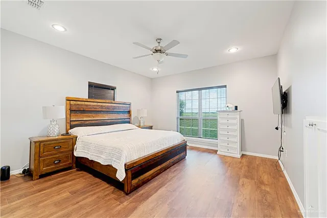 a bedroom with a bed and a dresser with wooden floor