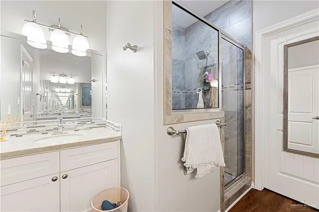 a bathroom with a granite countertop sink a mirror and a shower
