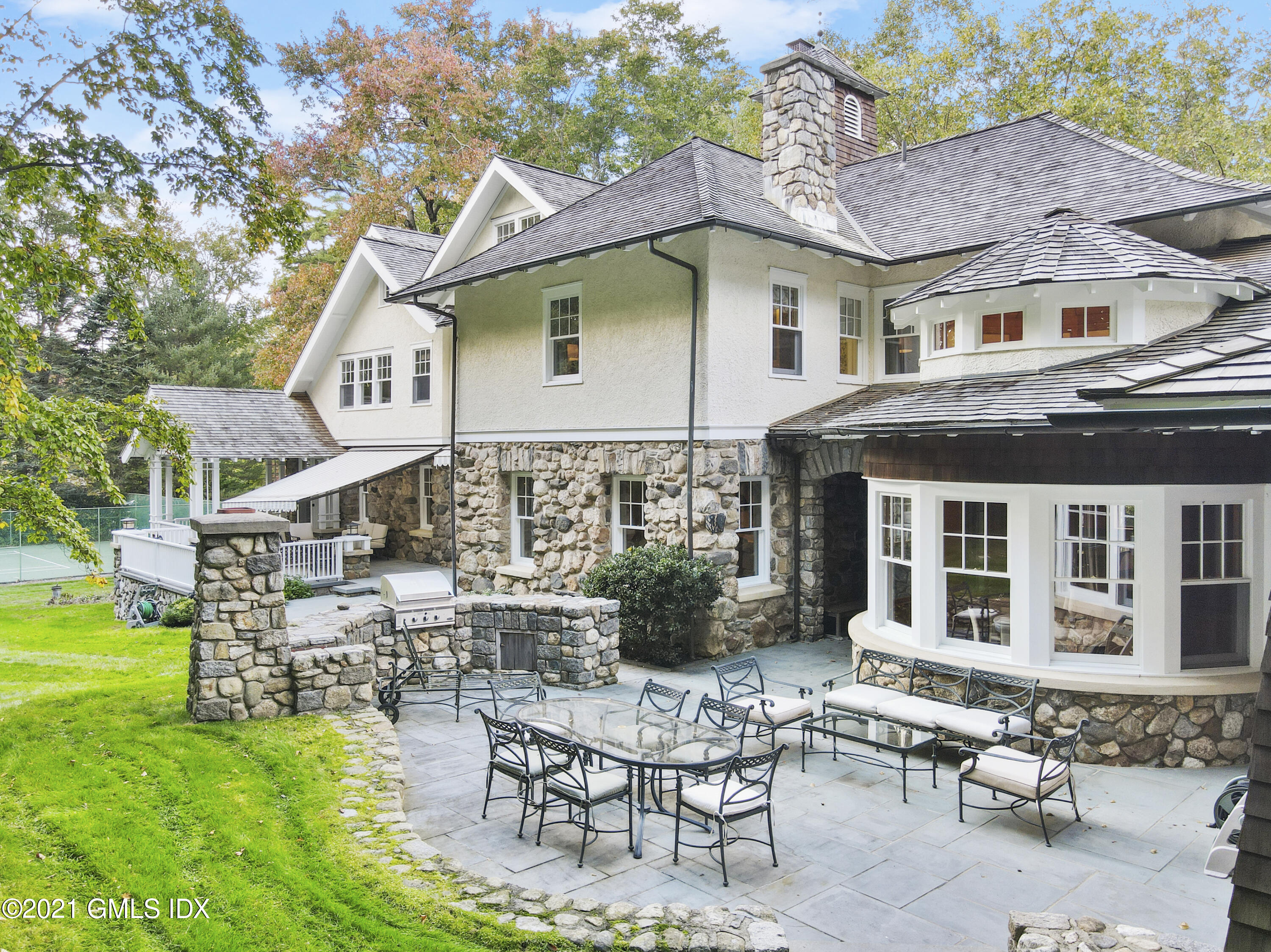 33 Brookridge Drive Greenwich, CT 06830 - Photo 31 of 44 a patio with a table and chairs and potted plants with large tree