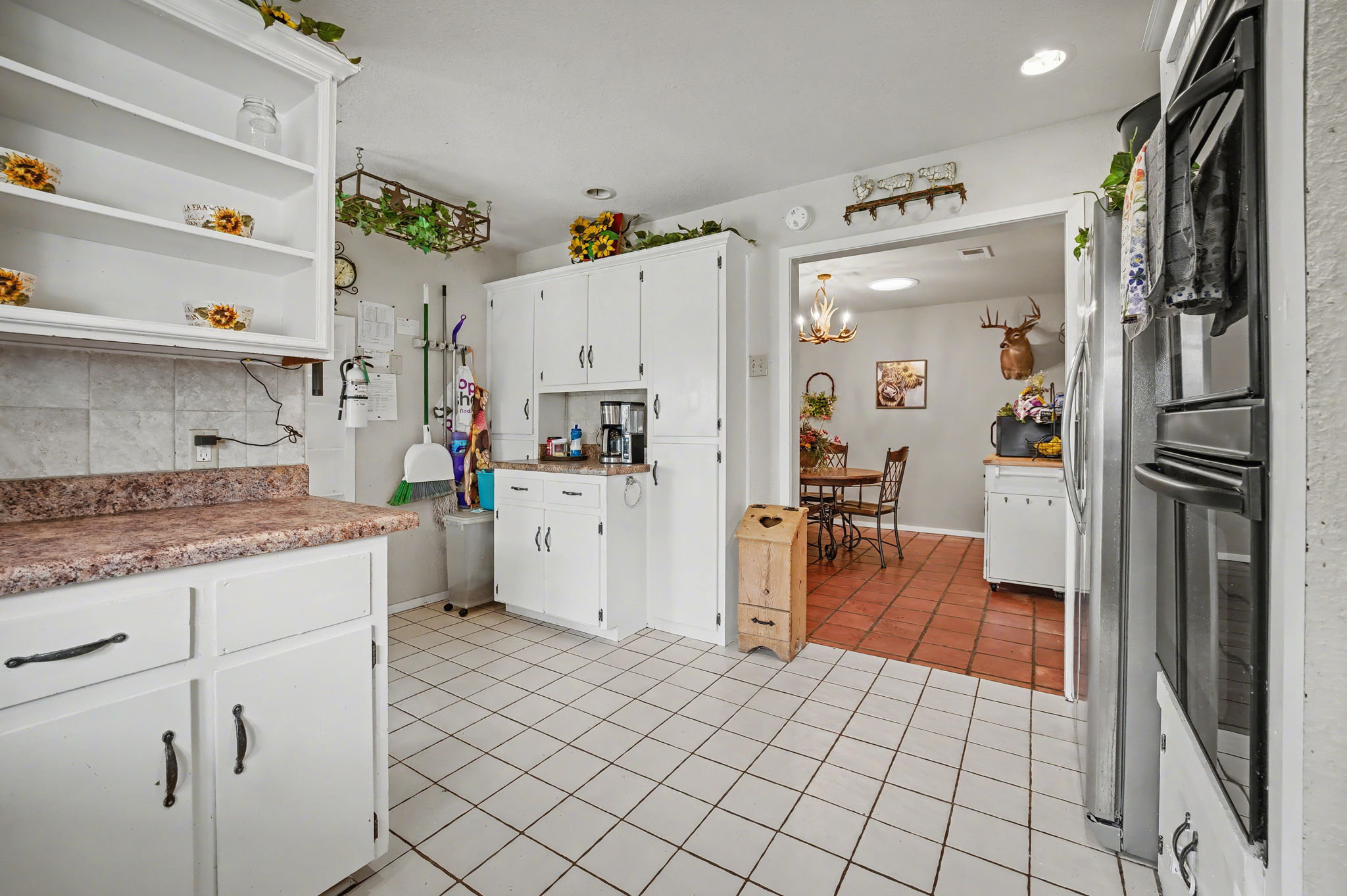103 Oak Ridge Circle Georgetown, TX 78628 - Photo 15 of 22 Kitchen featuring white cabinets, light tile patterned floors, tasteful backsplash, light countertops, and freestanding refrigerator