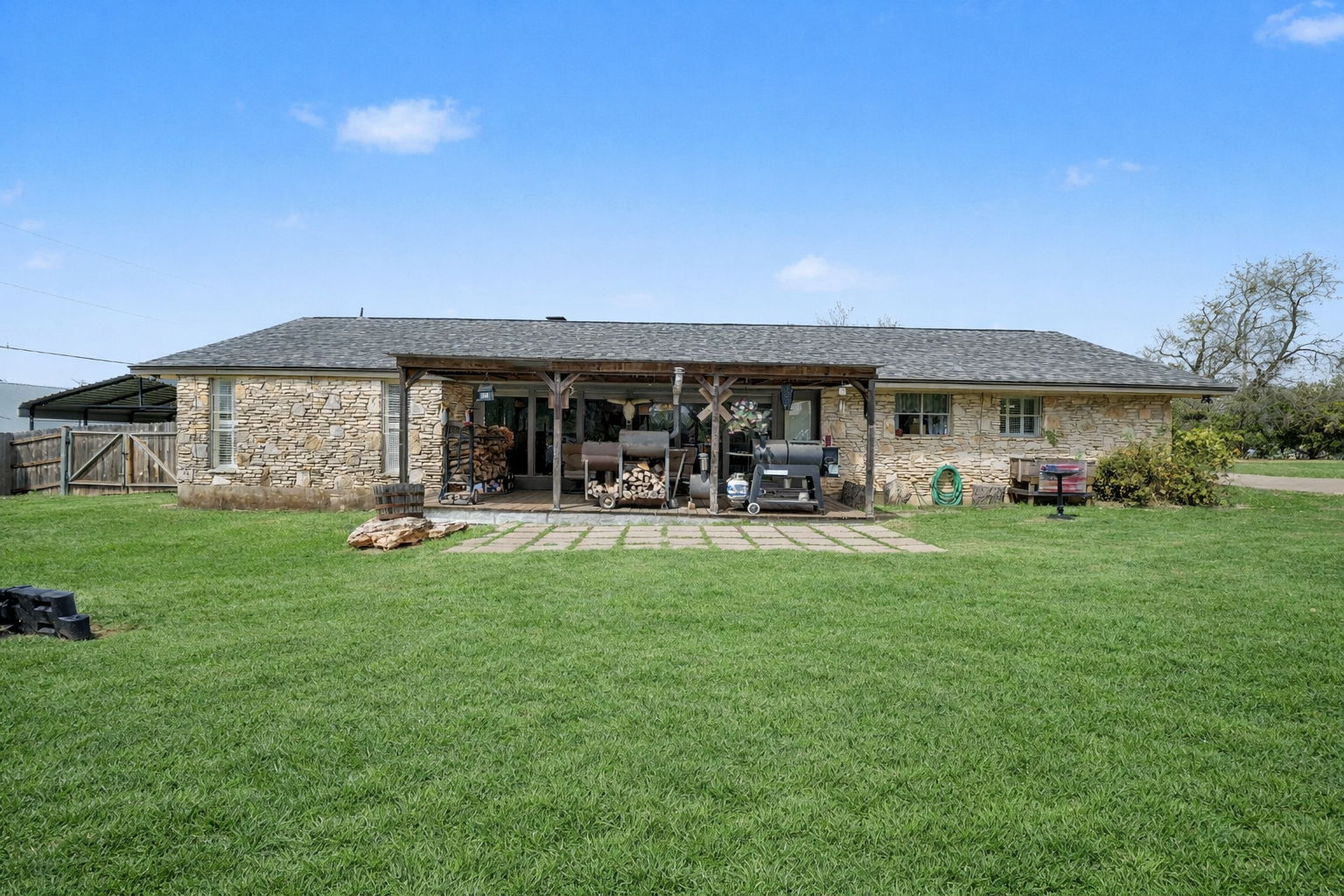 103 Oak Ridge Circle Georgetown, TX 78628 - Photo 3 of 22 Rear view of house featuring stone siding, a yard, a patio, and a shingled roof