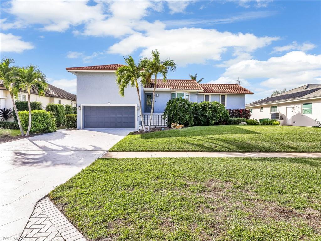 188 Columbus Way Marco Island, FL 34145 - Photo 2 of 38 View of front of house featuring concrete driveway, stucco siding, a front yard, a tiled roof, and a garage
