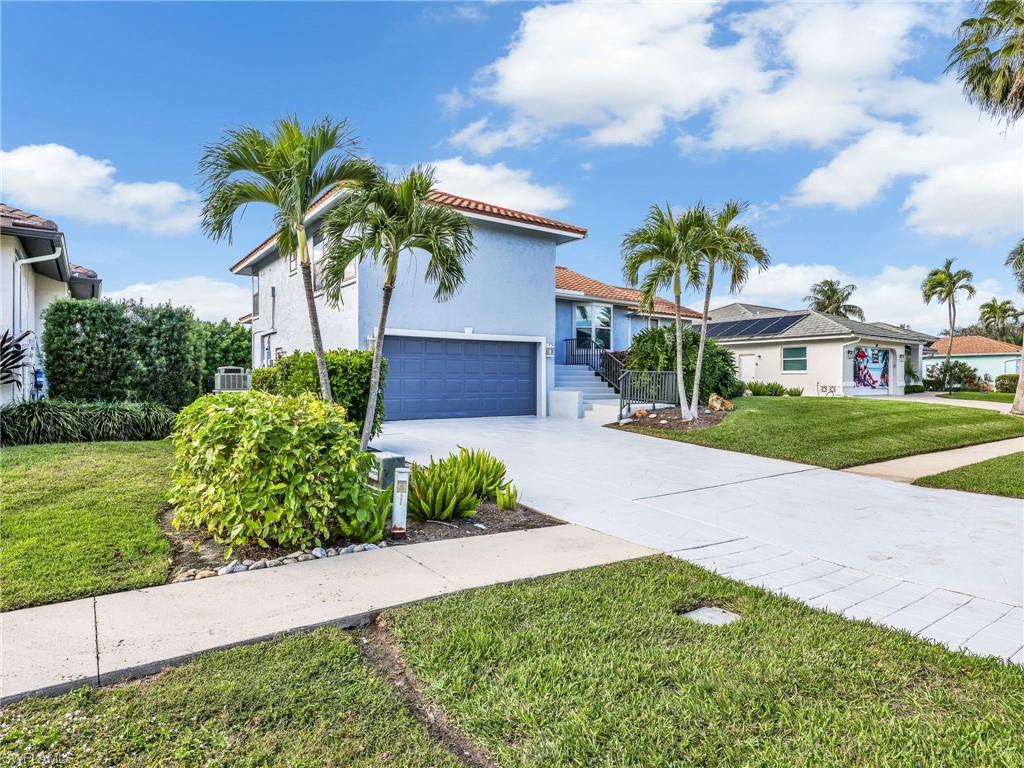 188 Columbus Way Marco Island, FL 34145 - Photo 31 of 38 Mediterranean / spanish-style home with stucco siding, a front lawn, concrete driveway, a tiled roof, and a garage