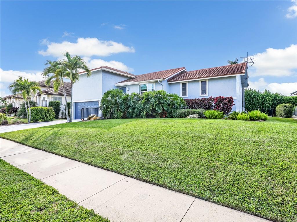 188 Columbus Way Marco Island, FL 34145 - Photo 32 of 38 Mediterranean / spanish house featuring a front yard, a tiled roof, stucco siding, an attached garage, and driveway