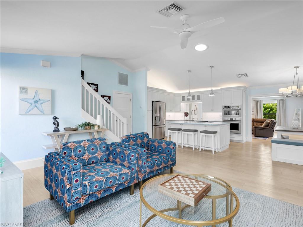 188 Columbus Way Marco Island, FL 34145 - Photo 6 of 38 Living area featuring ceiling fan, lofted ceiling, a chandelier, light wood finished floors, and stairs