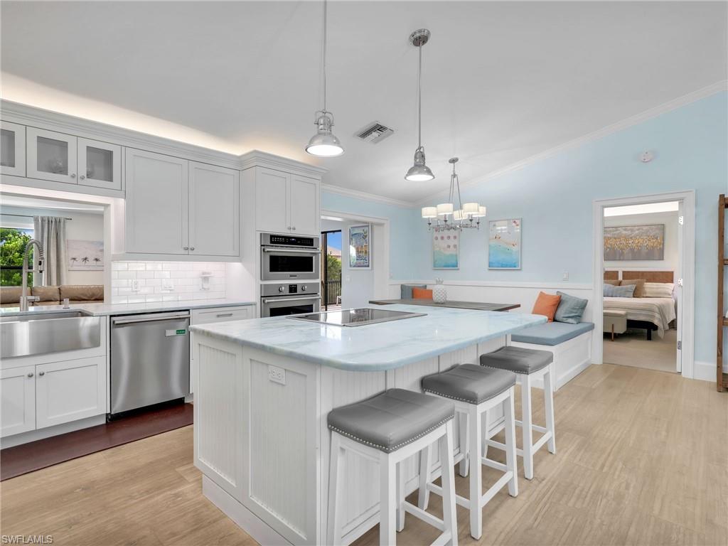 188 Columbus Way Marco Island, FL 34145 - Photo 8 of 38 Kitchen with lofted ceiling, a breakfast bar, white cabinets, ornamental molding, and a kitchen island