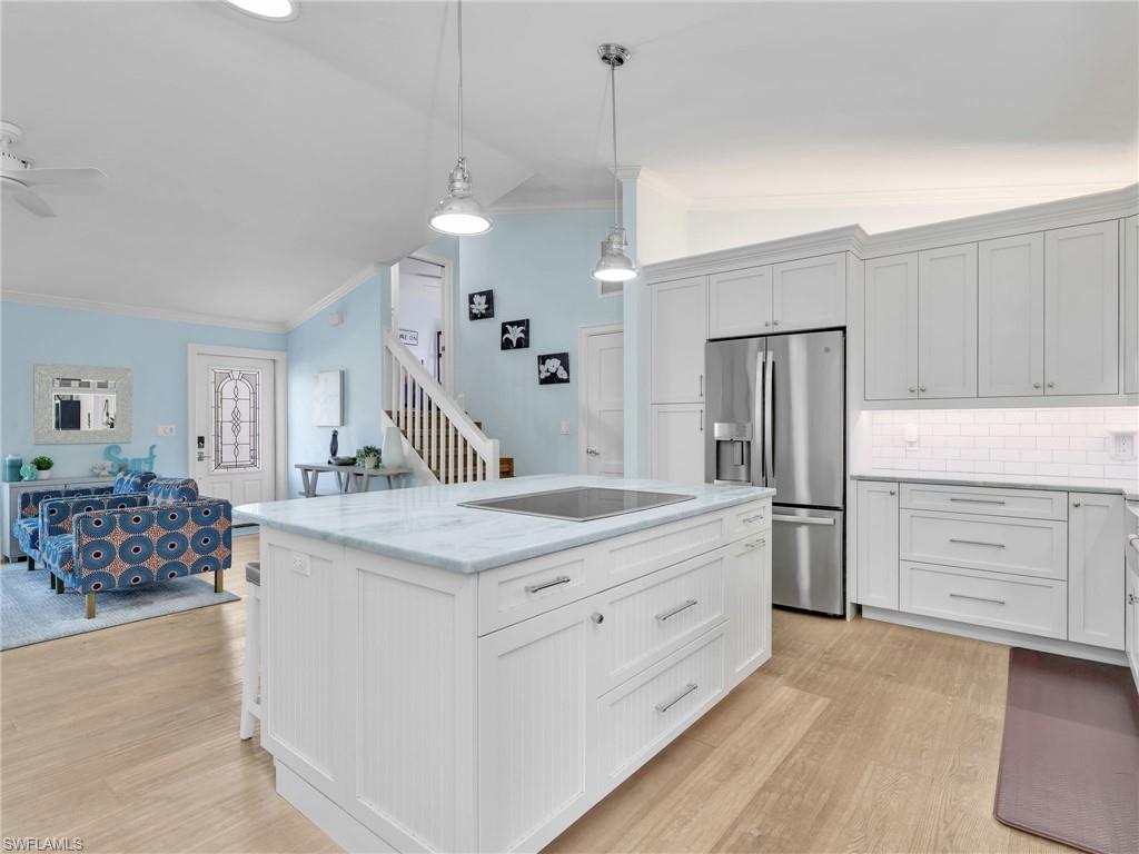 188 Columbus Way Marco Island, FL 34145 - Photo 38 of 38 Kitchen featuring vaulted ceiling, stainless steel fridge, crown molding, white cabinetry, and open floor plan