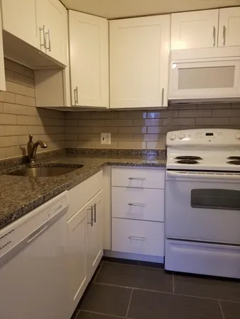 a kitchen with granite countertop white cabinets and white appliances