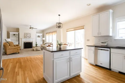 a kitchen with stainless steel appliances a refrigerator a stove a sink a dining table and chairs with wooden floor