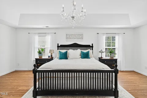 a bedroom with a large bed a chandelier and dresser
