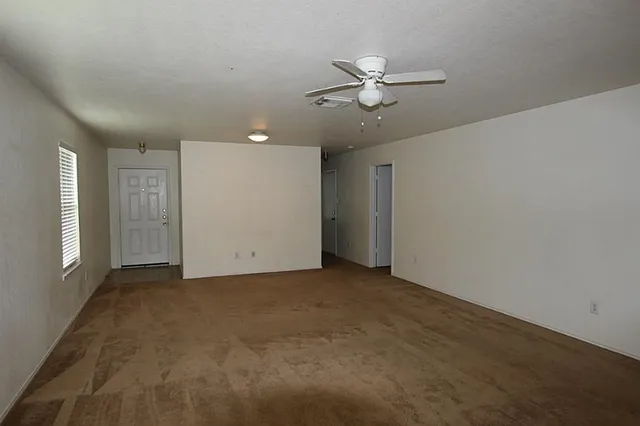 an empty room with fan walk in closet with window